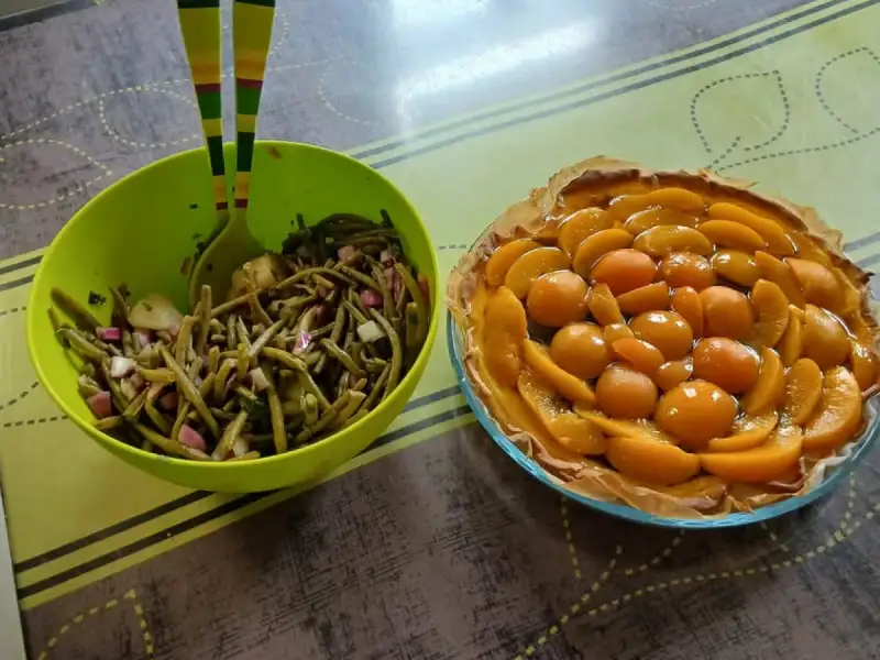 Salada de repolho com cebola roxa e pepino, em uma tigela verde, ao lado de uma torta de pêssego.
