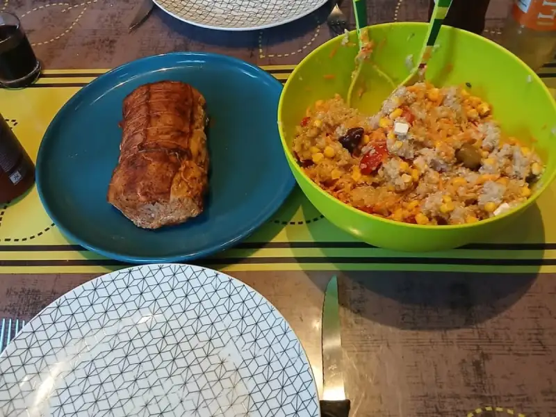 Salmão assado no forno, servido em uma travessa azul, ao lado de uma salada de arroz com milho, tomate, queijo feta e azeitonas.